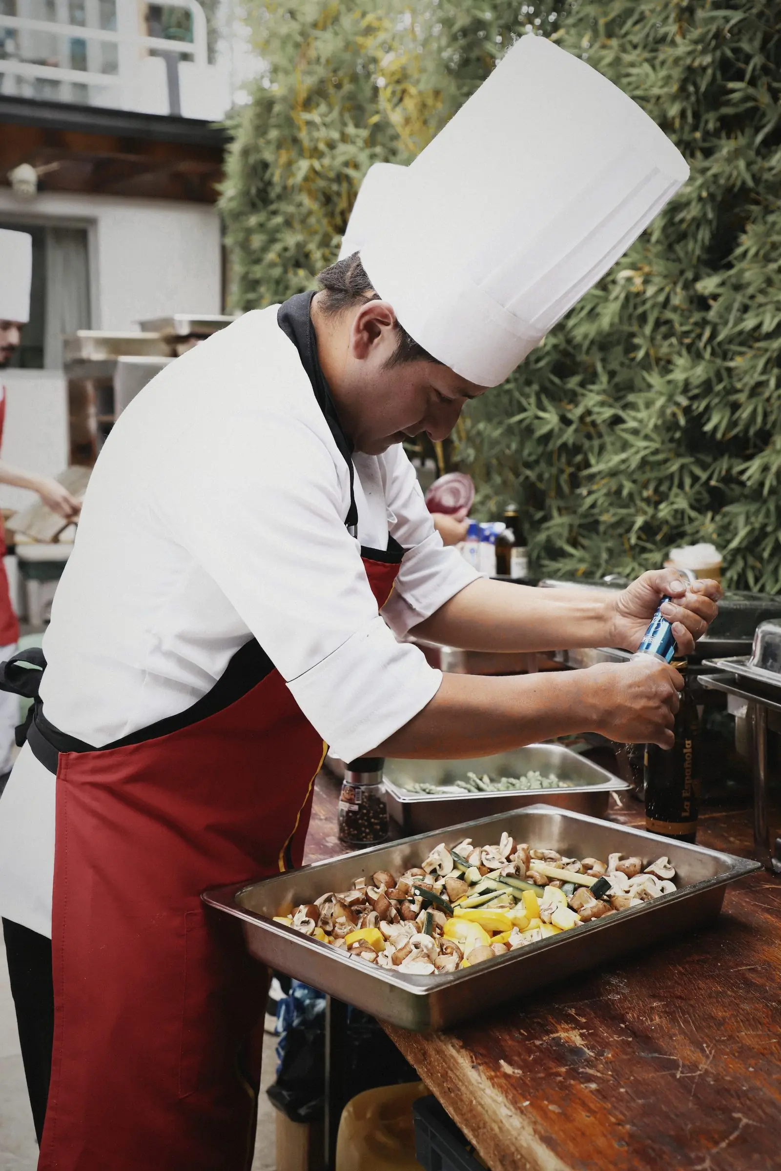 A chef finishing a tray of food at a wooden station.