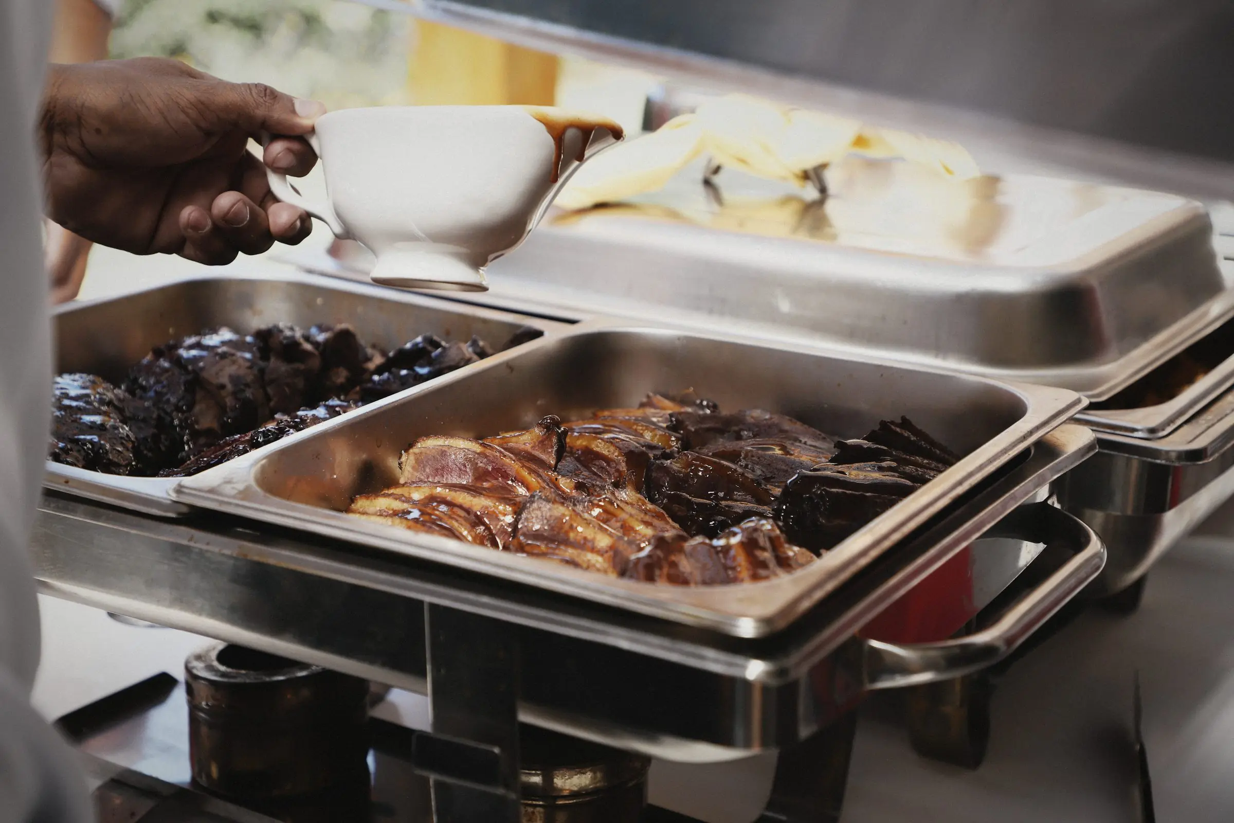 Steel trays of roasted meats and vegetables at the pass.